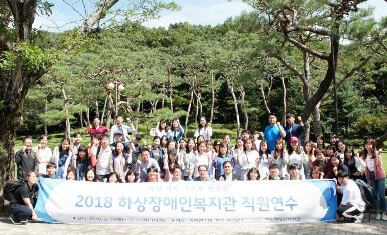 복지관 전직원이 연수원 잔디밭에서 현수막을 들고 찍은 사진