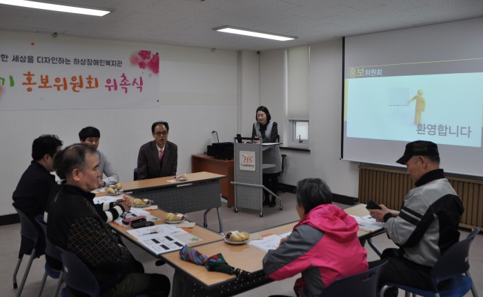 회의실에서 홍보위원과 직원이 둘러앉아 위촉식 시작 전 담당자의 소개를 듣고 있는 모습