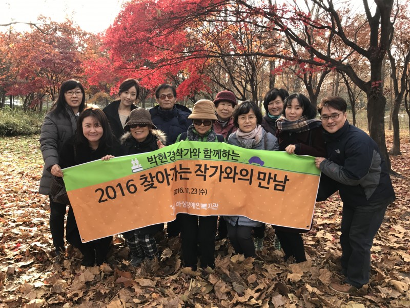 가을단풍을 배경으로 찾아가는 작가와의 만남에 참여한 모든 분들이 현수막을 들고 단체사진을 찍고 있는 모습