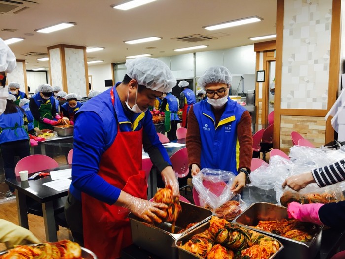 테이블 주변으로 봉사자들이 모여 이웃에게 전달할 김장김치를 버무리고 있는 모습