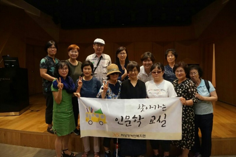 갤러리 실내에서 인문학 교실 참여자와 직원이 현수막을 들고 단체사진을 찍고 있는 모습