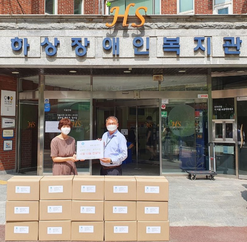 후원처 임직원 2명과 복지관 임직원 2명이 복지관 현관에서 후원품과 찍은 단체사진