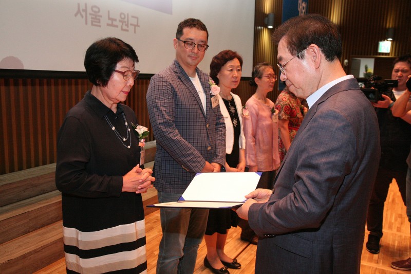 박원순 서울시장과 우선희 봉사자가 마주보고 서서 표창장을 주고 받는 사진